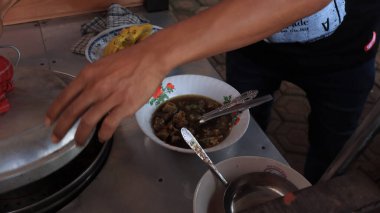 Bir soto lamongan satıcısı, 8 Ocak 2023 'te tezgahında bir menü hazırlıyor, Batang Endonezya.