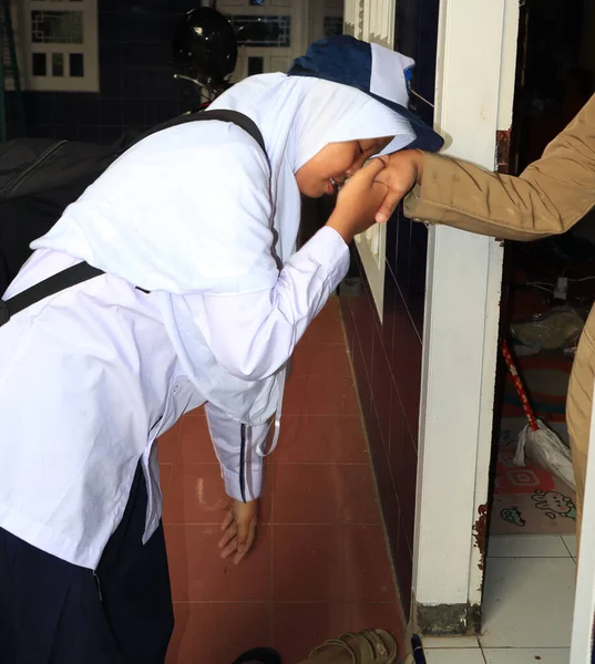 Junior high school students kissing their mother\'s hand to say goodbye to school