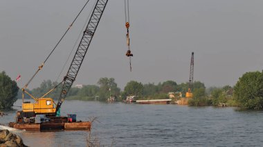 Nehrin ağzında ağır ekipmanlarla beton baraj inşaatı var.