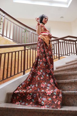 Güzel görünümlü Endonezyalı kadın tesettür takıyor ve Kebaya güzel bir batik kumaşa sarılmış.