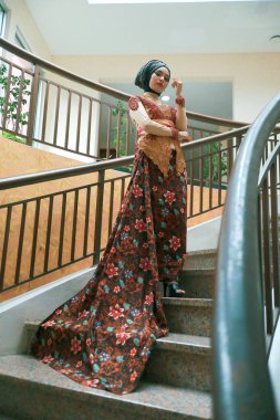 Güzel görünümlü Endonezyalı kadın tesettür takıyor ve Kebaya güzel bir batik kumaşa sarılmış.