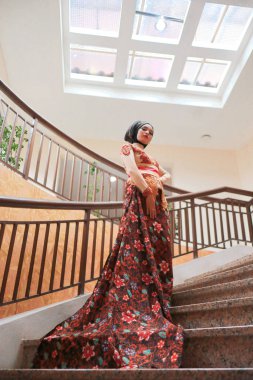 Güzel görünümlü Endonezyalı kadın tesettür takıyor ve Kebaya güzel bir batik kumaşa sarılmış.