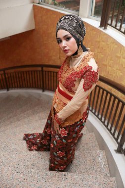 Güzel görünümlü Endonezyalı kadın tesettür takıyor ve Kebaya güzel bir batik kumaşa sarılmış.