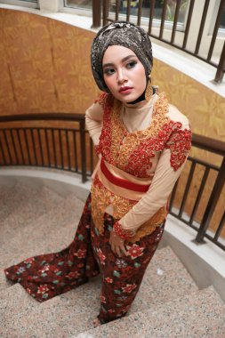 Güzel görünümlü Endonezyalı kadın tesettür takıyor ve Kebaya güzel bir batik kumaşa sarılmış.