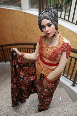 Güzel görünümlü Endonezyalı kadın tesettür takıyor ve Kebaya güzel bir batik kumaşa sarılmış.