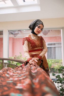 Güzel görünümlü Endonezyalı kadın tesettür takıyor ve Kebaya güzel bir batik kumaşa sarılmış.