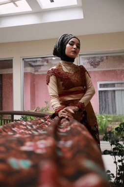 Güzel görünümlü Endonezyalı kadın tesettür takıyor ve Kebaya güzel bir batik kumaşa sarılmış.