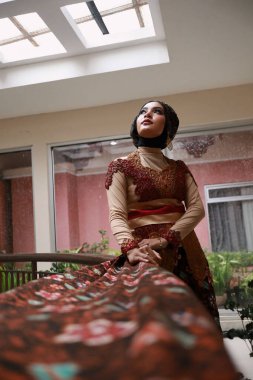 Güzel görünümlü Endonezyalı kadın tesettür takıyor ve Kebaya güzel bir batik kumaşa sarılmış.