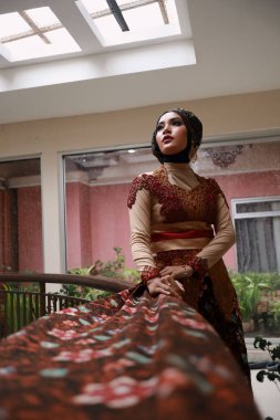 Güzel görünümlü Endonezyalı kadın tesettür takıyor ve Kebaya güzel bir batik kumaşa sarılmış.