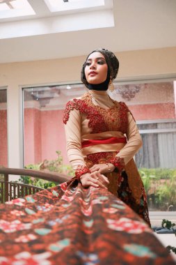Güzel görünümlü Endonezyalı kadın tesettür takıyor ve Kebaya güzel bir batik kumaşa sarılmış.