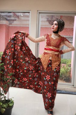 Güzel görünümlü Endonezyalı kadın tesettür takıyor ve Kebaya güzel bir batik kumaşa sarılmış.