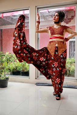 Güzel görünümlü Endonezyalı kadın tesettür takıyor ve Kebaya güzel bir batik kumaşa sarılmış.