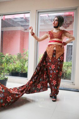 Güzel görünümlü Endonezyalı kadın tesettür takıyor ve Kebaya güzel bir batik kumaşa sarılmış.