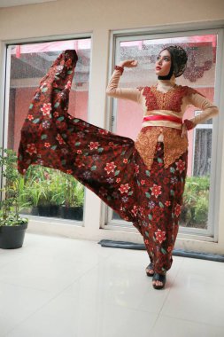 Güzel görünümlü Endonezyalı kadın tesettür takıyor ve Kebaya güzel bir batik kumaşa sarılmış.