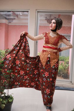 Güzel görünümlü Endonezyalı kadın tesettür takıyor ve Kebaya güzel bir batik kumaşa sarılmış.