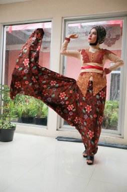 Güzel görünümlü Endonezyalı kadın tesettür takıyor ve Kebaya güzel bir batik kumaşa sarılmış.