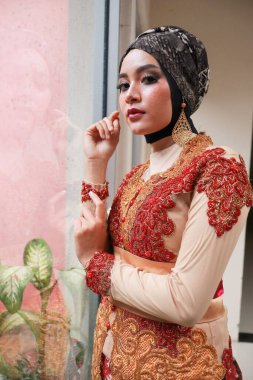 Güzel görünümlü Endonezyalı kadın tesettür takıyor ve Kebaya güzel bir batik kumaşa sarılmış.