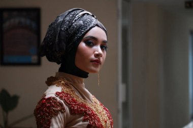 Güzel görünümlü Endonezyalı kadın tesettür takıyor ve Kebaya güzel bir batik kumaşa sarılmış.