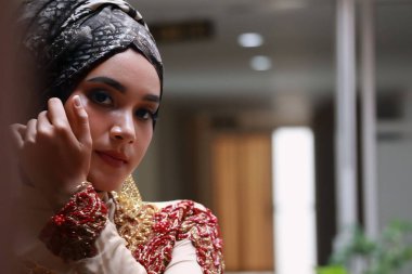 Güzel görünümlü Endonezyalı kadın tesettür takıyor ve Kebaya güzel bir batik kumaşa sarılmış.
