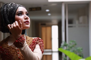 Güzel görünümlü Endonezyalı kadın tesettür takıyor ve Kebaya güzel bir batik kumaşa sarılmış.