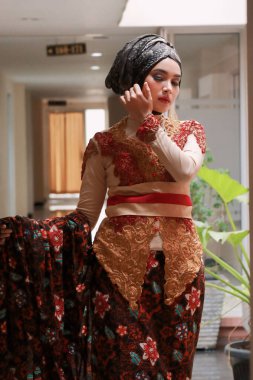 Güzel görünümlü Endonezyalı kadın tesettür takıyor ve Kebaya güzel bir batik kumaşa sarılmış.
