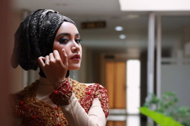 Güzel görünümlü Endonezyalı kadın tesettür takıyor ve Kebaya güzel bir batik kumaşa sarılmış.
