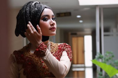 Güzel görünümlü Endonezyalı kadın tesettür takıyor ve Kebaya güzel bir batik kumaşa sarılmış.