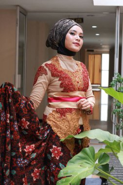 Güzel görünümlü Endonezyalı kadın tesettür takıyor ve Kebaya güzel bir batik kumaşa sarılmış.