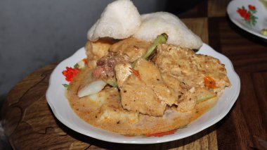 Lenthog Tanjung, a dish made from pieces of lontong, jackfruit, tempeh and tofu. Served on a plate covered in banana leaves with a savory taste. clipart