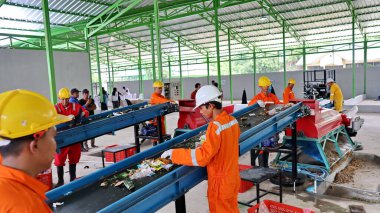 Geri dönüşümlü materyalleri sınıflandırmak için atık işleme fabrikasında çalışırken güvenlik kıyafeti ve kask giyen işçilerin portresi, Pekalongan Endonezya 10 Ocak 2025