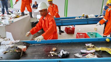 Geri dönüşümlü materyalleri sınıflandırmak için atık işleme fabrikasında çalışırken güvenlik kıyafeti ve kask giyen işçilerin portresi, Pekalongan Endonezya 10 Ocak 2025