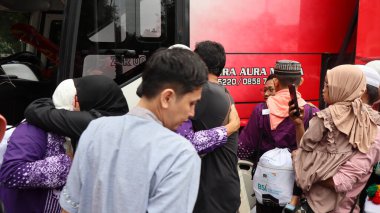 Endonezyalı Müslüman hacılar için sevinçli bir an. Aile ve arkadaşlar, tur otobüsünün yanında birbirlerini duygularıyla selamlarlar. İslam geleneği ve birliğinin kutlanması, Pekalongan, Endonezya, 19 Haziran 2025