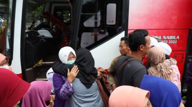 Endonezyalı Müslüman hacılar için sevinçli bir an. Aile ve arkadaşlar, tur otobüsünün yanında birbirlerini duygularıyla selamlarlar. İslam geleneği ve birliğinin kutlanması, Pekalongan, Endonezya, 19 Haziran 2025
