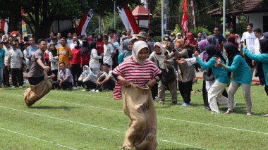 Endonezya Bağımsızlık Günü kutlamaları sırasında bir çuval yarışı yarışına katılan kadınlar ve erkekler. 14 Ağustos 2025 'te Pekalongan, Orta Cava' da neşeli takım çalışması ve yerel gelenek.