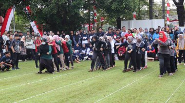 Şenlikli kalabalık ve ulusal gururla heyecanlı bir takım oyunu. Erkekler, Endonezya Bağımsızlık Günü kutlamaları sırasında 14 Ağustos 2025 'te Pekalongan, Orta Java' da geleneksel bir bakiak yarışında yarışıyorlar..