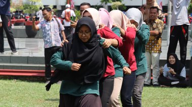 Şenlikli kalabalık ve ulusal gururla heyecanlı bir takım oyunu. Erkekler, Endonezya Bağımsızlık Günü kutlamaları sırasında 14 Ağustos 2025 'te Pekalongan, Orta Java' da geleneksel bir bakiak yarışında yarışıyorlar..