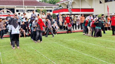 Şenlikli kalabalık ve ulusal gururla heyecanlı bir takım oyunu. Erkekler, Endonezya Bağımsızlık Günü kutlamaları sırasında 14 Ağustos 2025 'te Pekalongan, Orta Java' da geleneksel bir bakiak yarışında yarışıyorlar..