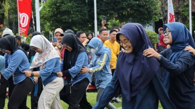 Şenlikli kalabalık ve ulusal gururla heyecanlı bir takım oyunu. Erkekler, Endonezya Bağımsızlık Günü kutlamaları sırasında 14 Ağustos 2025 'te Pekalongan, Orta Java' da geleneksel bir bakiak yarışında yarışıyorlar..