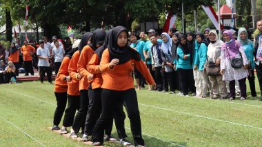 Şenlikli kalabalık ve ulusal gururla heyecanlı bir takım oyunu. Erkekler, Endonezya Bağımsızlık Günü kutlamaları sırasında 14 Ağustos 2025 'te Pekalongan, Orta Java' da geleneksel bir bakiak yarışında yarışıyorlar..
