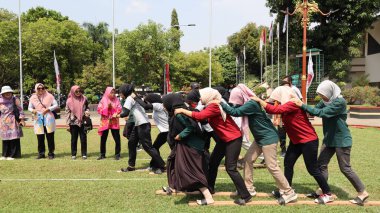 Şenlikli kalabalık ve ulusal gururla heyecanlı bir takım oyunu. Erkekler, Endonezya Bağımsızlık Günü kutlamaları sırasında 14 Ağustos 2025 'te Pekalongan, Orta Java' da geleneksel bir bakiak yarışında yarışıyorlar..