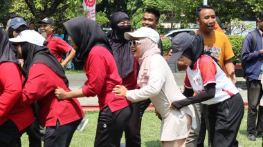 Şenlikli kalabalık ve ulusal gururla heyecanlı bir takım oyunu. Erkekler, Endonezya Bağımsızlık Günü kutlamaları sırasında 14 Ağustos 2025 'te Pekalongan, Orta Java' da geleneksel bir bakiak yarışında yarışıyorlar..