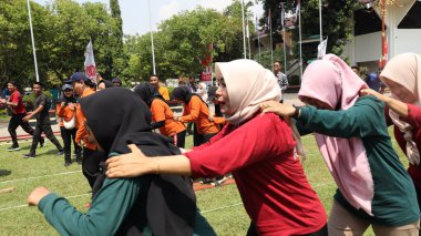 Şenlikli kalabalık ve ulusal gururla heyecanlı bir takım oyunu. Erkekler, Endonezya Bağımsızlık Günü kutlamaları sırasında 14 Ağustos 2025 'te Pekalongan, Orta Java' da geleneksel bir bakiak yarışında yarışıyorlar..