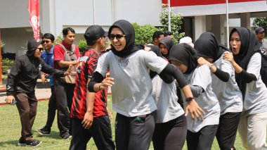 Şenlikli kalabalık ve ulusal gururla heyecanlı bir takım oyunu. Erkekler, Endonezya Bağımsızlık Günü kutlamaları sırasında 14 Ağustos 2025 'te Pekalongan, Orta Java' da geleneksel bir bakiak yarışında yarışıyorlar..