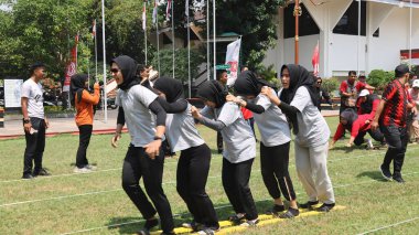 Şenlikli kalabalık ve ulusal gururla heyecanlı bir takım oyunu. Erkekler, Endonezya Bağımsızlık Günü kutlamaları sırasında 14 Ağustos 2025 'te Pekalongan, Orta Java' da geleneksel bir bakiak yarışında yarışıyorlar..