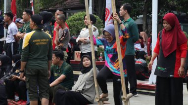 Şenlikli kalabalık ve ulusal gururla heyecanlı bir takım oyunu. Erkekler, Endonezya Bağımsızlık Günü kutlamaları sırasında 14 Ağustos 2025 'te Pekalongan, Orta Java' da geleneksel bir bakiak yarışında yarışıyorlar..