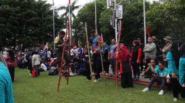 Şenlikli kalabalık ve ulusal gururla heyecanlı bir takım oyunu. Erkekler, Endonezya Bağımsızlık Günü kutlamaları sırasında 14 Ağustos 2025 'te Pekalongan, Orta Java' da geleneksel bir bakiak yarışında yarışıyorlar..