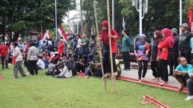 Şenlikli kalabalık ve ulusal gururla heyecanlı bir takım oyunu. Erkekler, Endonezya Bağımsızlık Günü kutlamaları sırasında 14 Ağustos 2025 'te Pekalongan, Orta Java' da geleneksel bir bakiak yarışında yarışıyorlar..