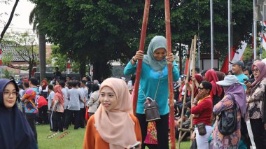 Şenlikli kalabalık ve ulusal gururla heyecanlı bir takım oyunu. Erkekler, Endonezya Bağımsızlık Günü kutlamaları sırasında 14 Ağustos 2025 'te Pekalongan, Orta Java' da geleneksel bir bakiak yarışında yarışıyorlar..