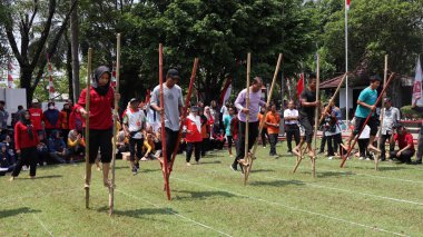 Şenlikli kalabalık ve ulusal gururla heyecanlı bir takım oyunu. Erkekler, Endonezya Bağımsızlık Günü kutlamaları sırasında 14 Ağustos 2025 'te Pekalongan, Orta Java' da geleneksel bir bakiak yarışında yarışıyorlar..