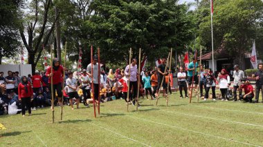 Şenlikli kalabalık ve ulusal gururla heyecanlı bir takım oyunu. Erkekler, Endonezya Bağımsızlık Günü kutlamaları sırasında 14 Ağustos 2025 'te Pekalongan, Orta Java' da geleneksel bir bakiak yarışında yarışıyorlar..